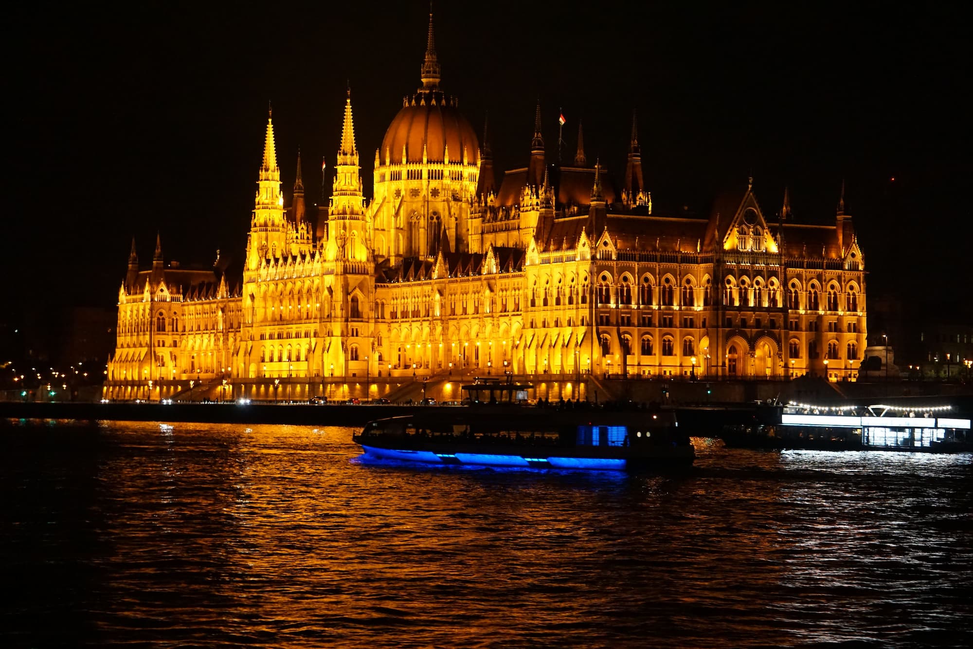 Vista del parlamento húngaro iluminado a orillas del río Danubio en Budapest de noche