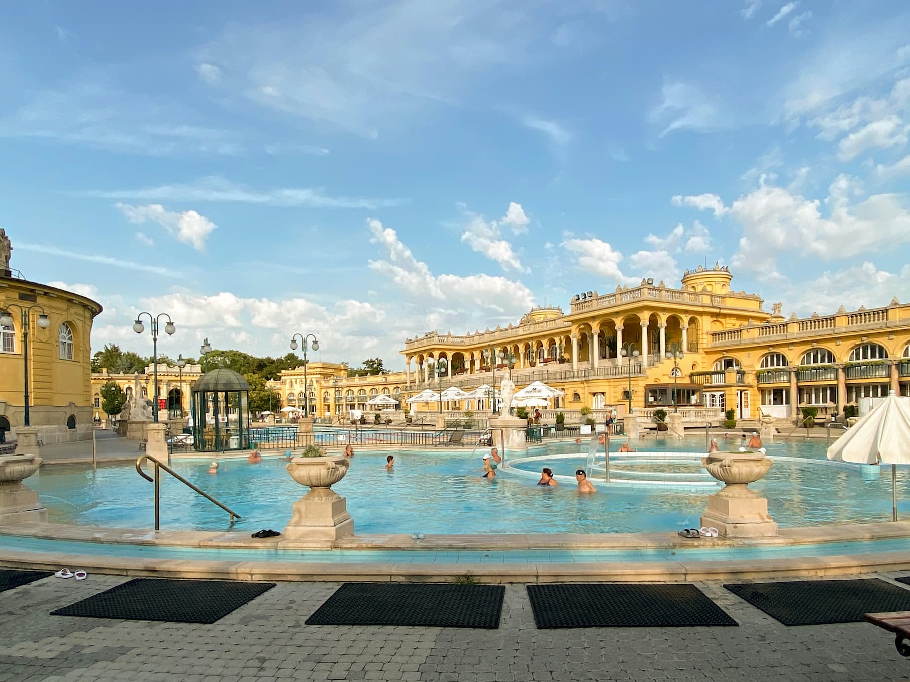 Albercas exteriores y edificio amarillo neobarroco de los baños termales Széchenyi en Budapest
