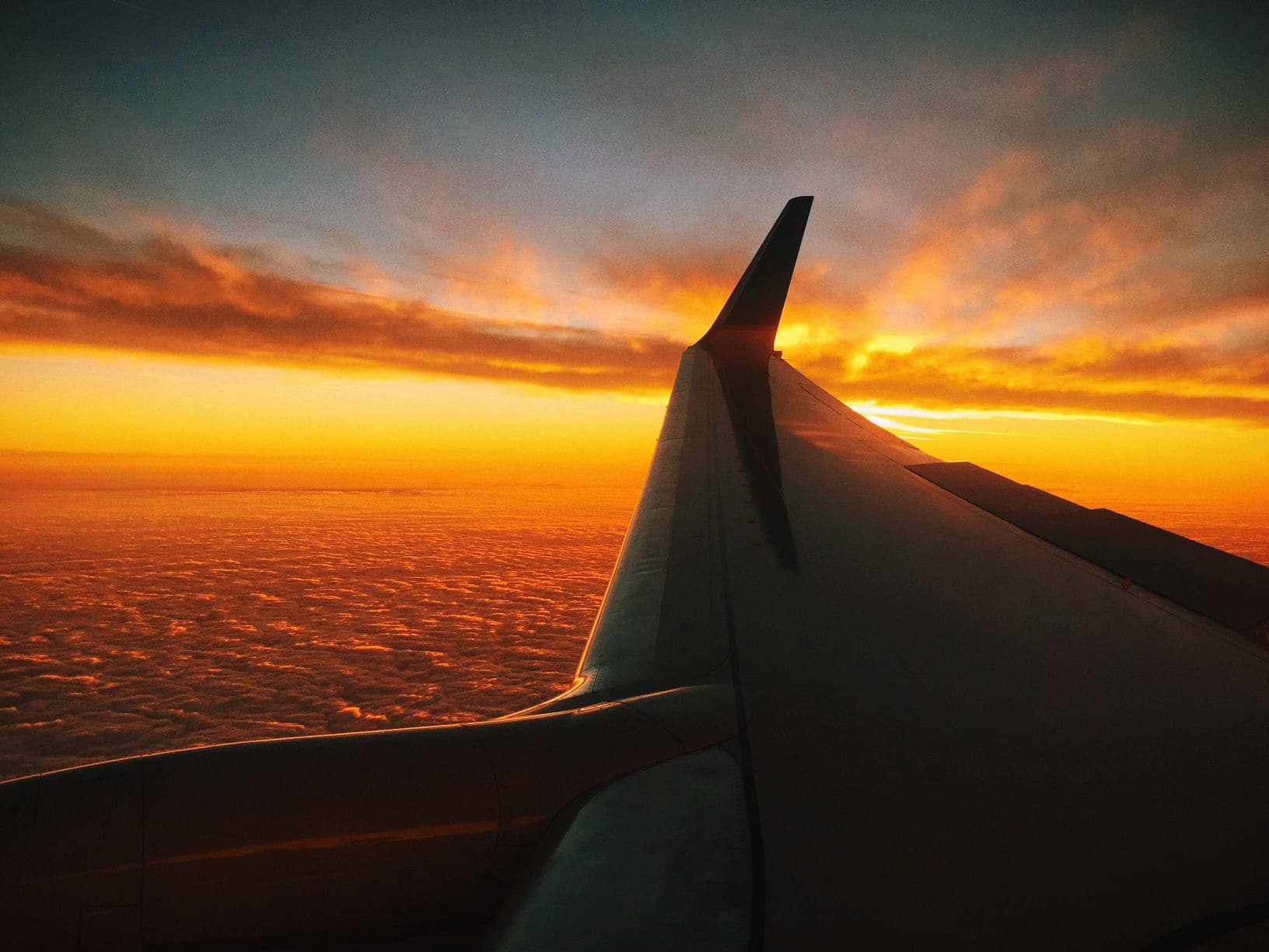 Ala de avión sobre nubes doradas durante el amanecer en vuelo comercial