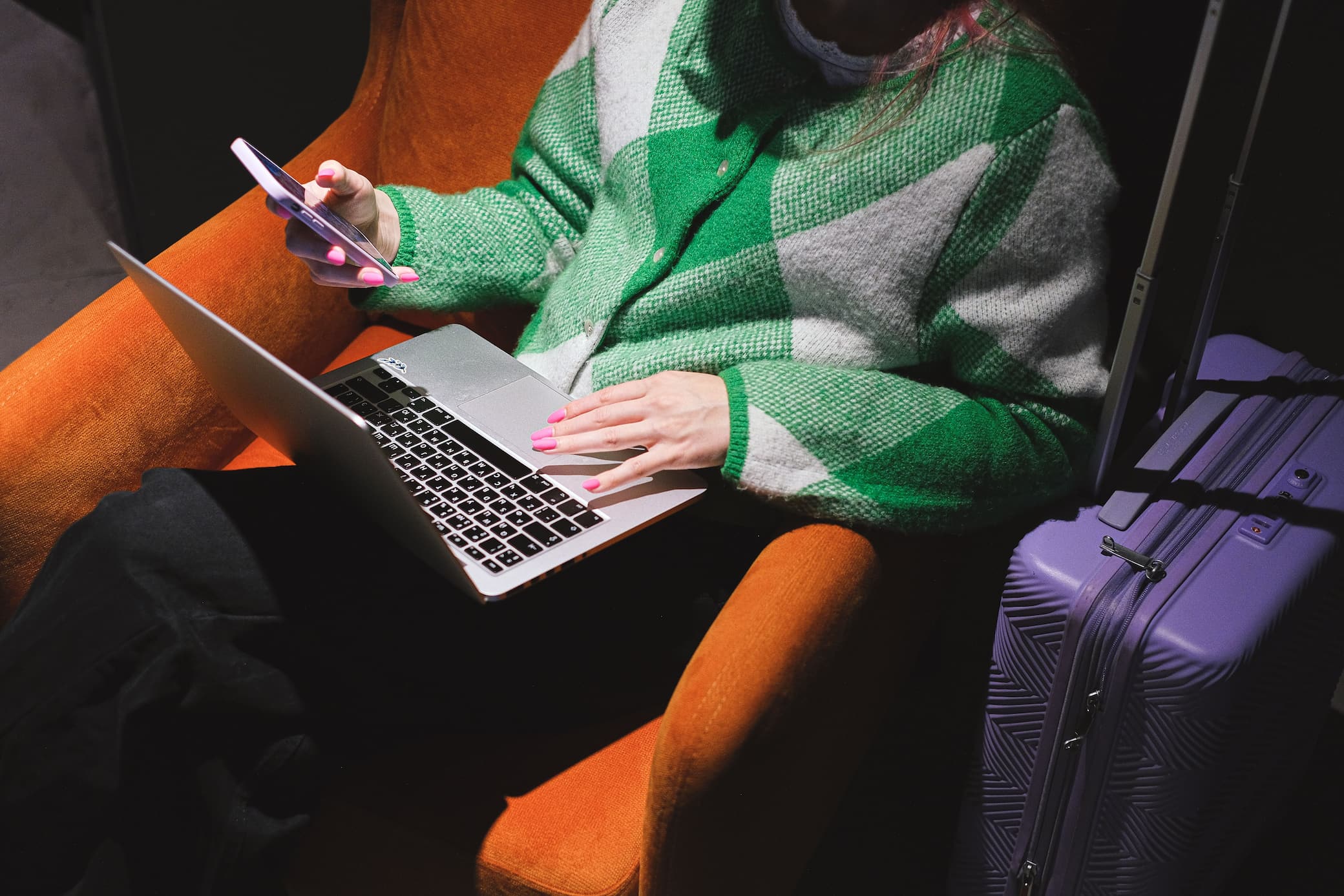 Pasajero consultando ofertas de vuelos baratos en su smartphone y laptop